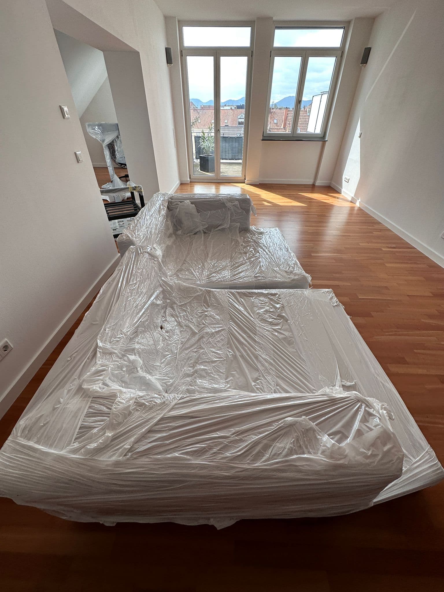 Mit Schutzfolie abgedecktes Sofa in einer leergeräumten Wohnung